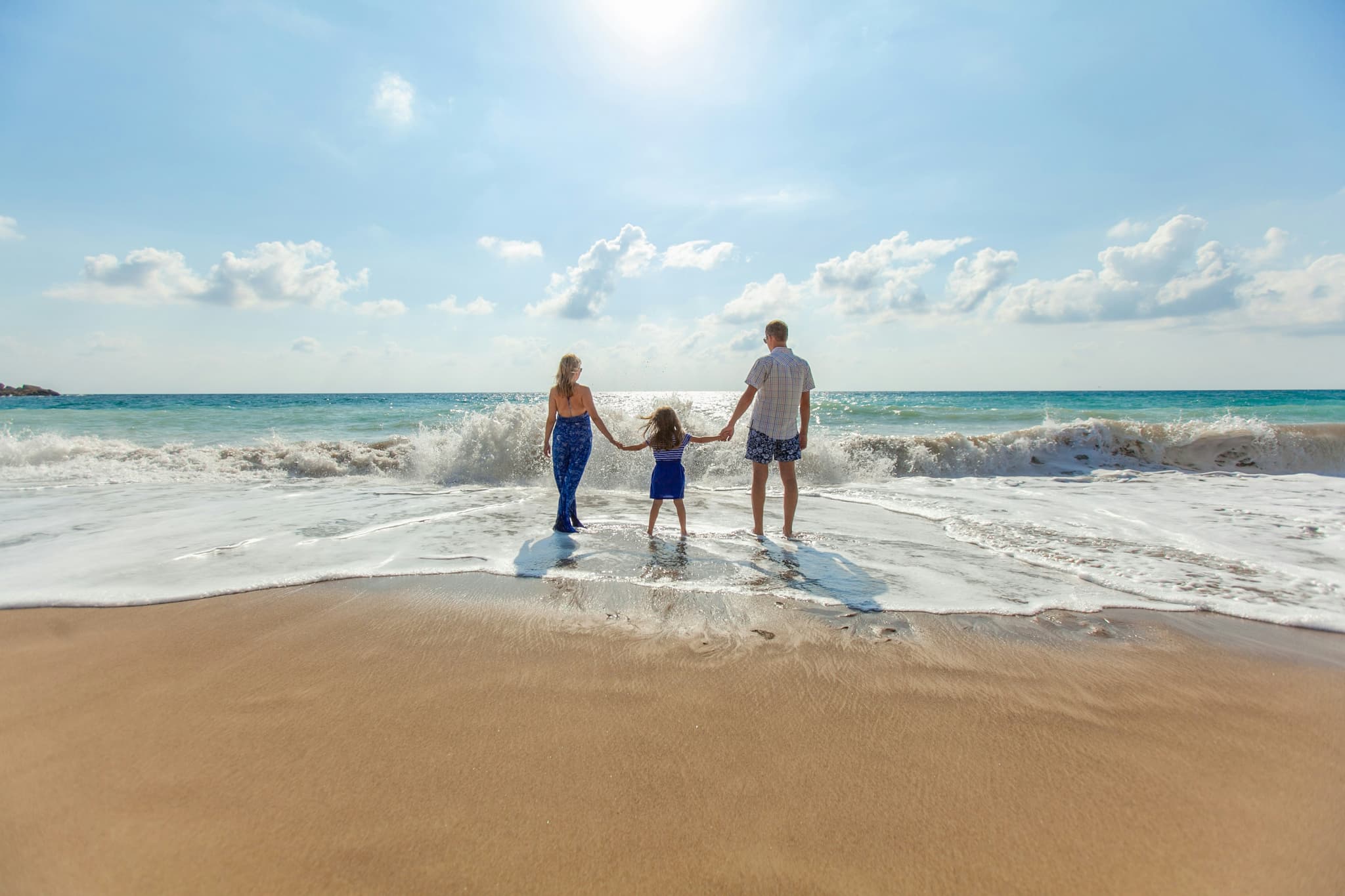 Family holding hands in the surf at sunrise